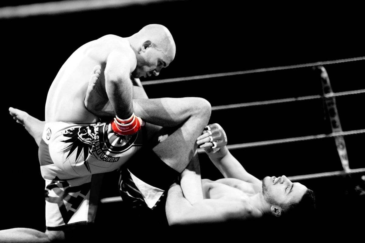 Combat de MMA en cage, un athlète contrôle son adversaire au sol